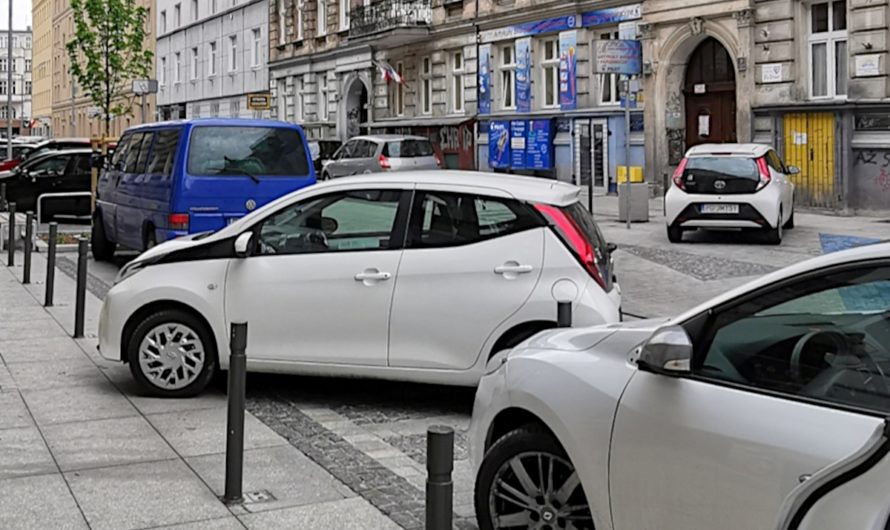 Dwa białe samochody parkują nielegalnie. Choć zamontowano sporo słupków, to kilka miejsc pozostaje niezabezpieczonych